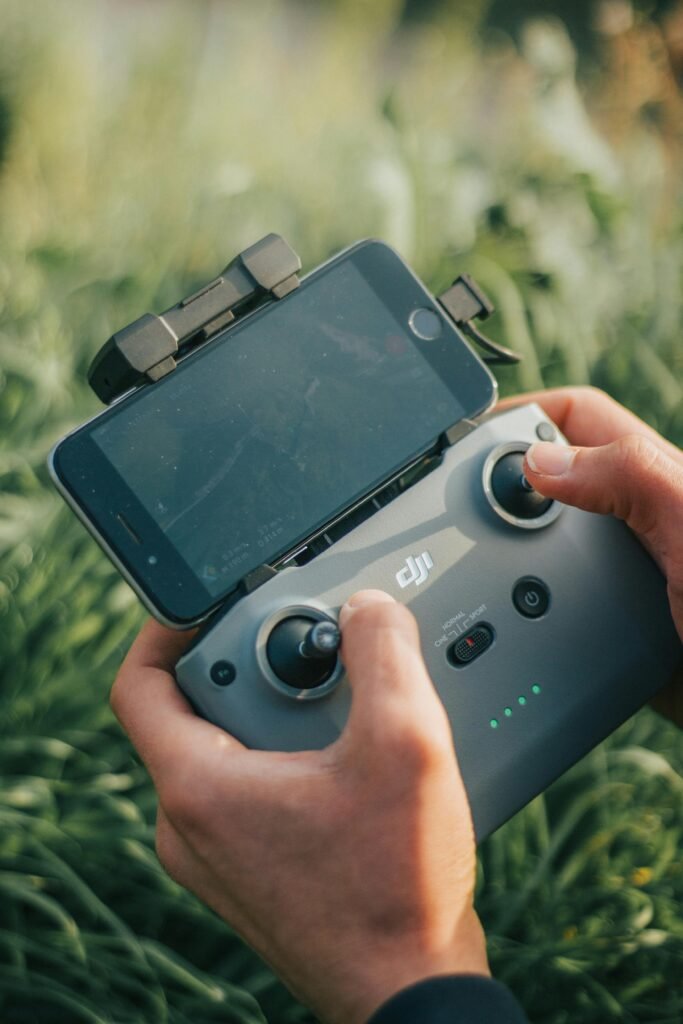 Close-up of hands holding a drone controller attached to a smartphone amidst greenery.